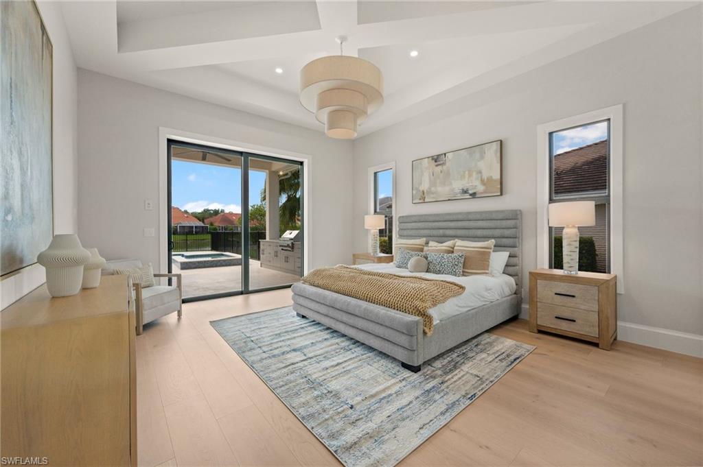 207 Monterey Drive Naples, FL 34119 - Photo 16 of 47 a spacious bedroom with a large bed and a chandelier