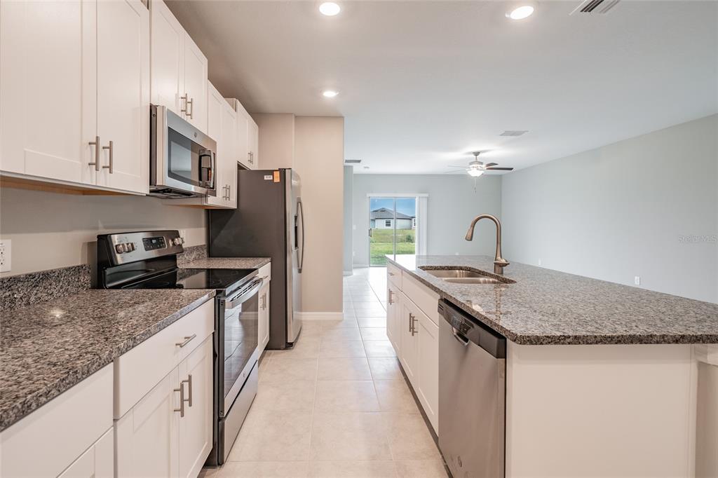 31807 Barrel Wave Way Wesley Chapel, FL 33545 - Photo 12 of 61 a kitchen with stainless steel appliances granite countertop a sink stove and refrigerator