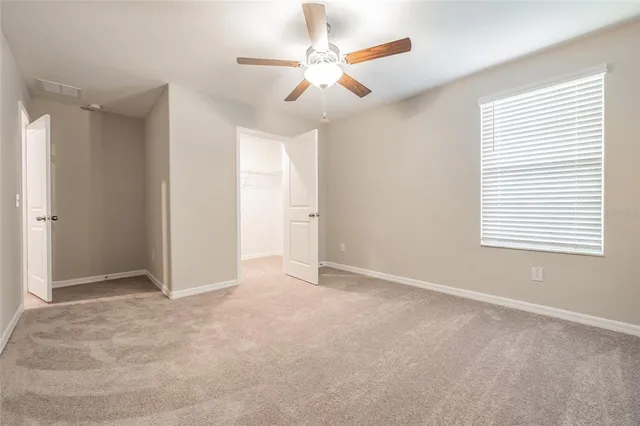 an empty room with a window and a fan