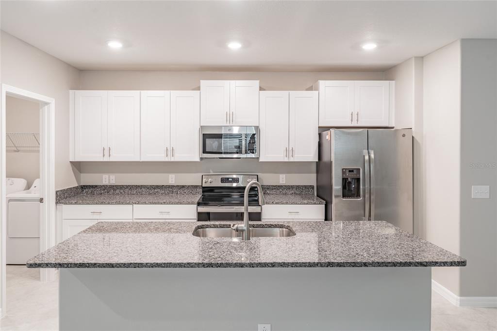 31807 Barrel Wave Way Wesley Chapel, FL 33545 - Photo 8 of 61 a kitchen with kitchen island granite countertop a sink a refrigerator and a counter top space