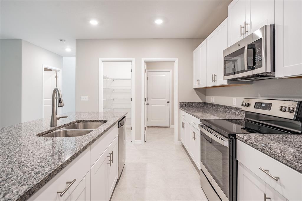 31807 Barrel Wave Way Wesley Chapel, FL 33545 - Photo 10 of 61 a kitchen with granite countertop stainless steel appliances a stove sink and microwave