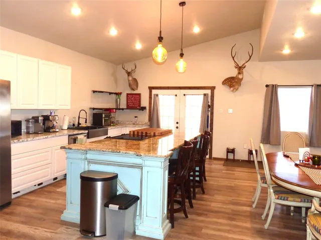 a kitchen with stainless steel appliances granite countertop a stove a sink a dining table and chairs with wooden floor