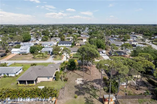 an aerial view of a residential houses with outdoor space and trees all around