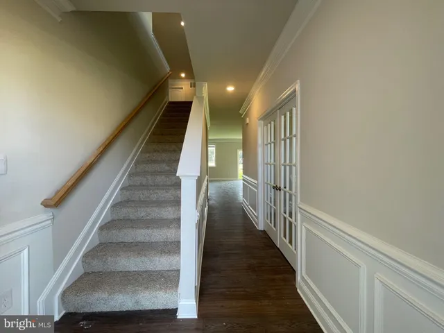 a view of staircase with lots of frames on wall and wooden floor