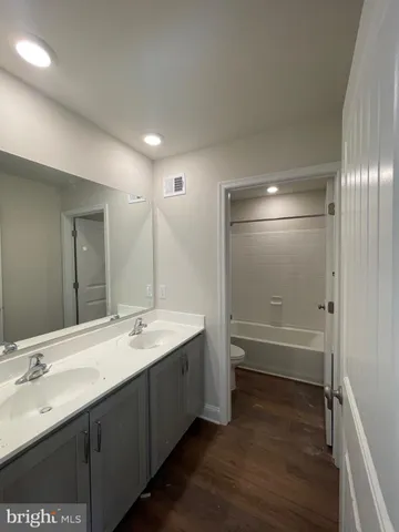 a bathroom with a double vanity sink a mirror and a bathtub