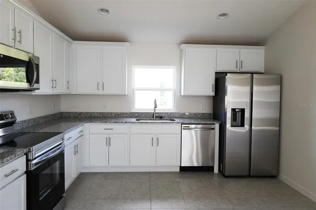 a kitchen with stainless steel appliances granite countertop a refrigerator sink and stove