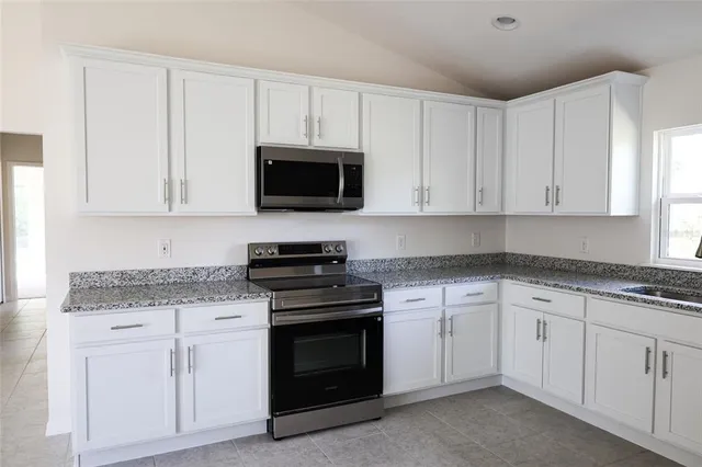 a kitchen with granite countertop white cabinets and stainless steel appliances