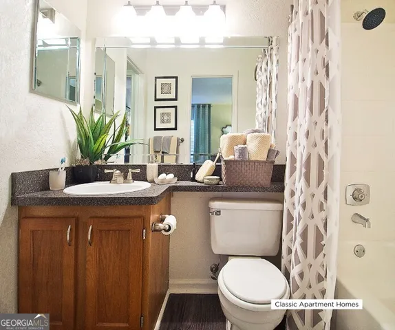 a bathroom with a granite countertop sink a toilet and a mirror