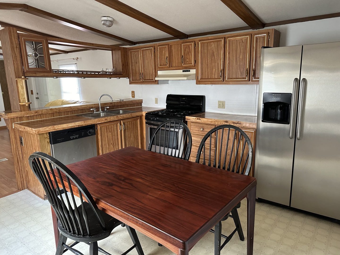 10557 North State Rte 50, Unit 11 Manteno, IL 60950 - Photo 6 of 11 a kitchen with stainless steel appliances granite countertop a stove a sink dishwasher a dining table and chairs with wooden floor