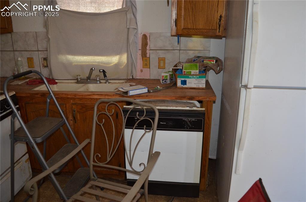 1604 County Road R Rush, CO 80833 - Photo 14 of 16 Kitchen with a sink, brown cabinets, decorative backsplash, and white appliances