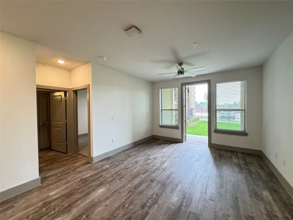 a view of an empty room with a window and wooden floor