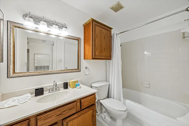 a bathroom with a granite countertop sink mirror vanity toilet and bathtub