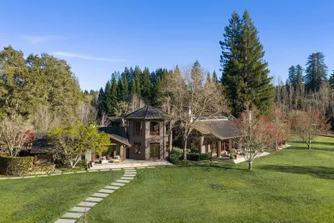 a front view of a house with a garden and trees