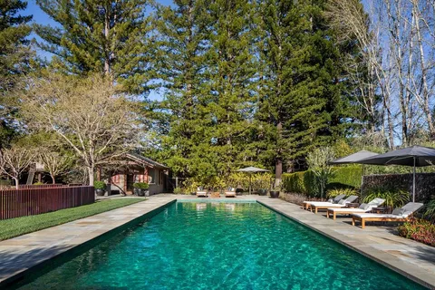 a view of a swimming pool with lawn chairs under an umbrella