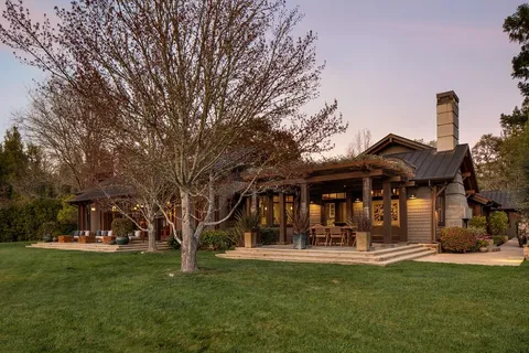 a front view of a house with a garden and trees