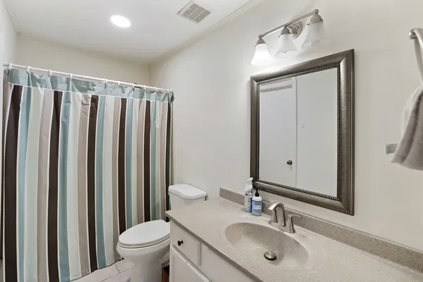 a bathroom with a granite countertop sink vanity mirror and toilet