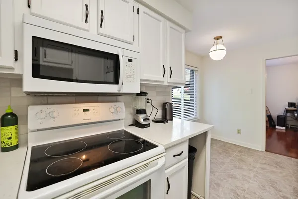 a kitchen with white cabinets a sink and appliances