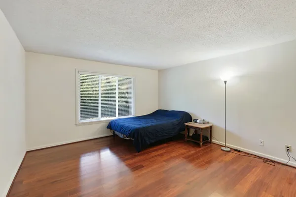 a view of a hallway with wooden floor and a bathroom