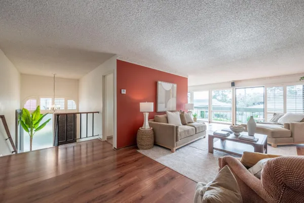 a living room with furniture floor to ceiling window and wooden floor