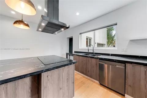 a kitchen with stainless steel appliances granite countertop a sink and a black white countertops with wooden floor