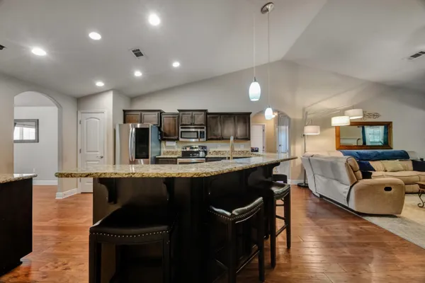 a kitchen with stainless steel appliances granite countertop a sink a stove and a wooden floors