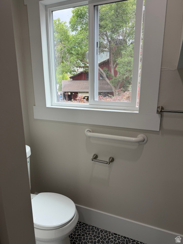 8965 Quail Run Drive Sandy, UT 84093 - Photo 48 of 56 Bathroom featuring a white toilet, pebble-style flooring, a sliding window with white trim, a towel bar, and a grab bar