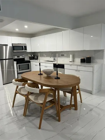 a kitchen with a table chairs microwave and cabinets