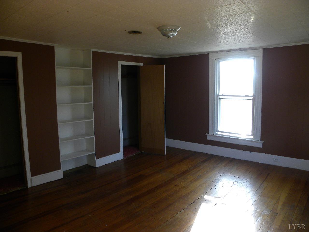 5797 Scuffletown Road Randolph, VA 23962 - Photo 11 of 18 an empty room with wooden floor and windows with curtains