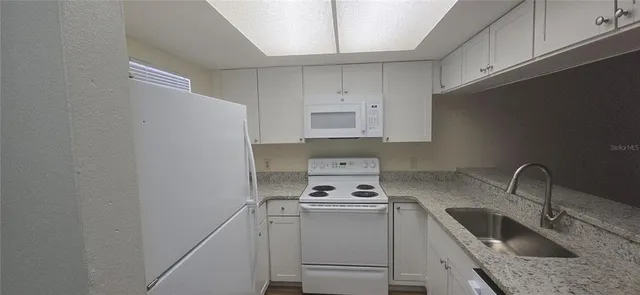 a kitchen with sink a microwave and cabinets