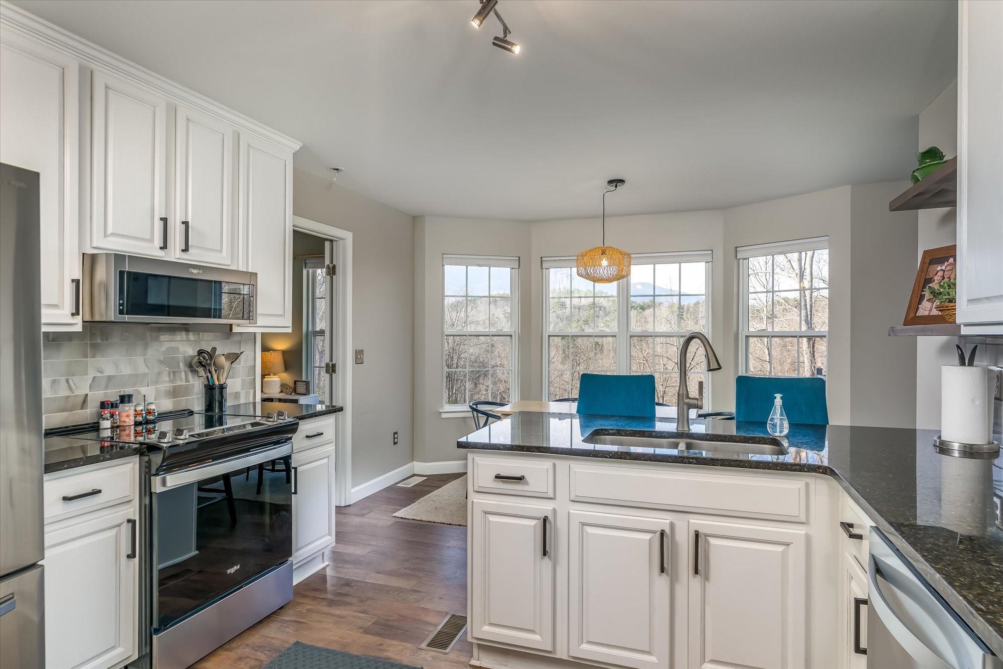 531 Sloping Meadow Mill Spring, NC 28756 - Photo 10 of 46 a kitchen with stainless steel appliances a white cabinets and a stove top oven