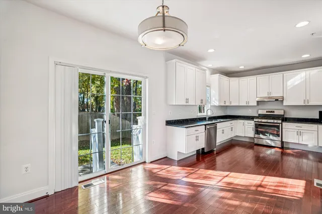 an open kitchen with wooden floor and stainless steel appliances