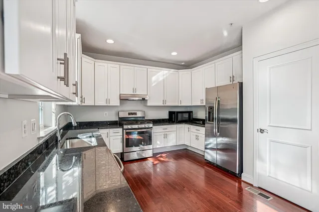 a view of a kitchen with refrigerator and wooden floor