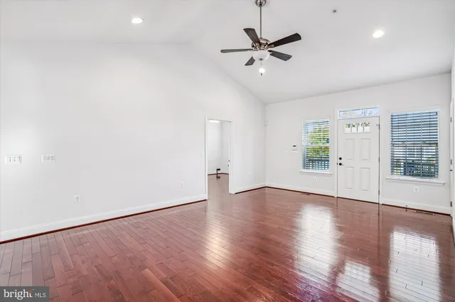 a view of an empty room with wooden floor and a window