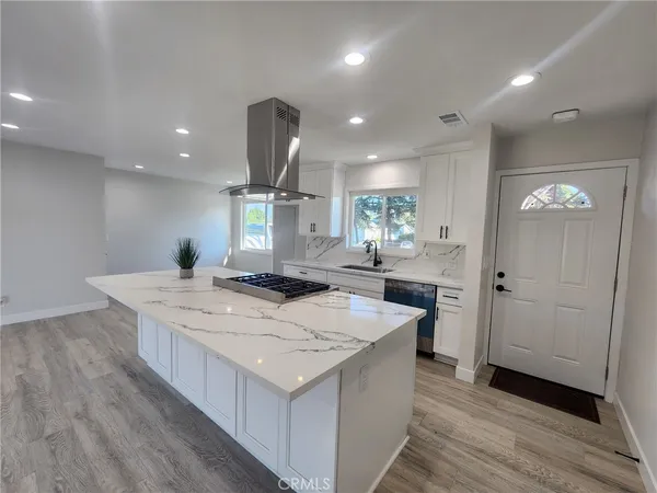 a large kitchen with stainless steel appliances a large counter top and a wooden floors