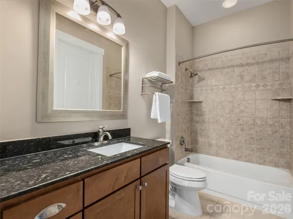 a bathroom with a granite countertop sink toilet a large mirror a bathtub and shower