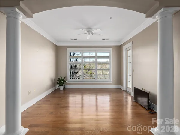 a view of an empty room with wooden floor and a window
