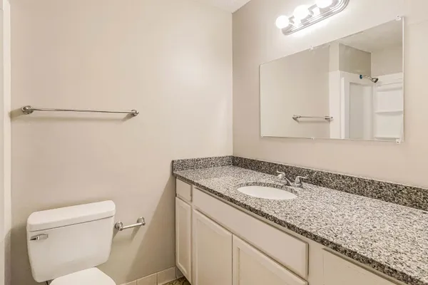 a bathroom with a granite countertop sink a toilet and a mirror