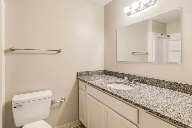 a bathroom with a granite countertop sink a toilet and a mirror