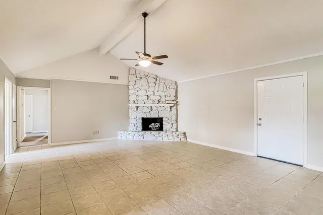 a view of empty room with a fireplace and chandelier fan