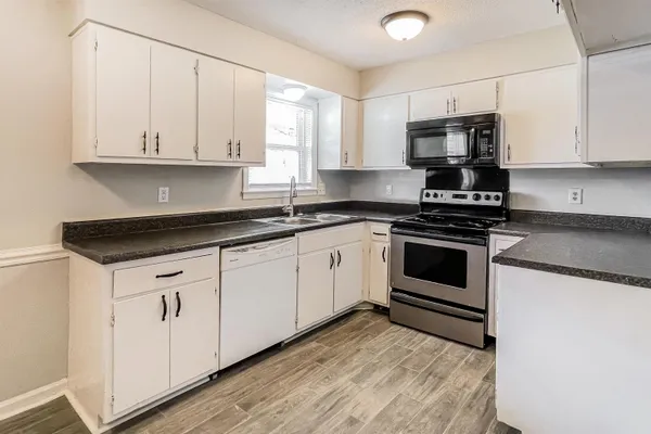 a kitchen with granite countertop white cabinets and white appliances