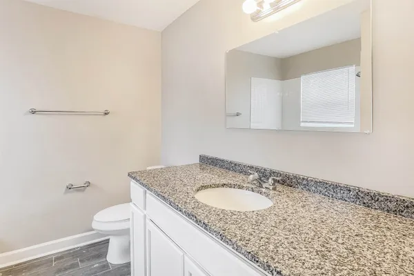 a bathroom with a granite countertop sink and a toilet