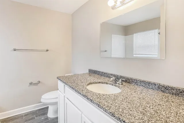 a bathroom with a granite countertop sink and a toilet
