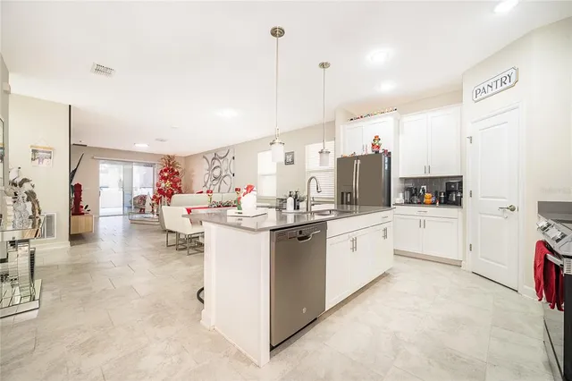 a kitchen with stainless steel appliances kitchen island granite countertop a table chairs refrigerator and microwave