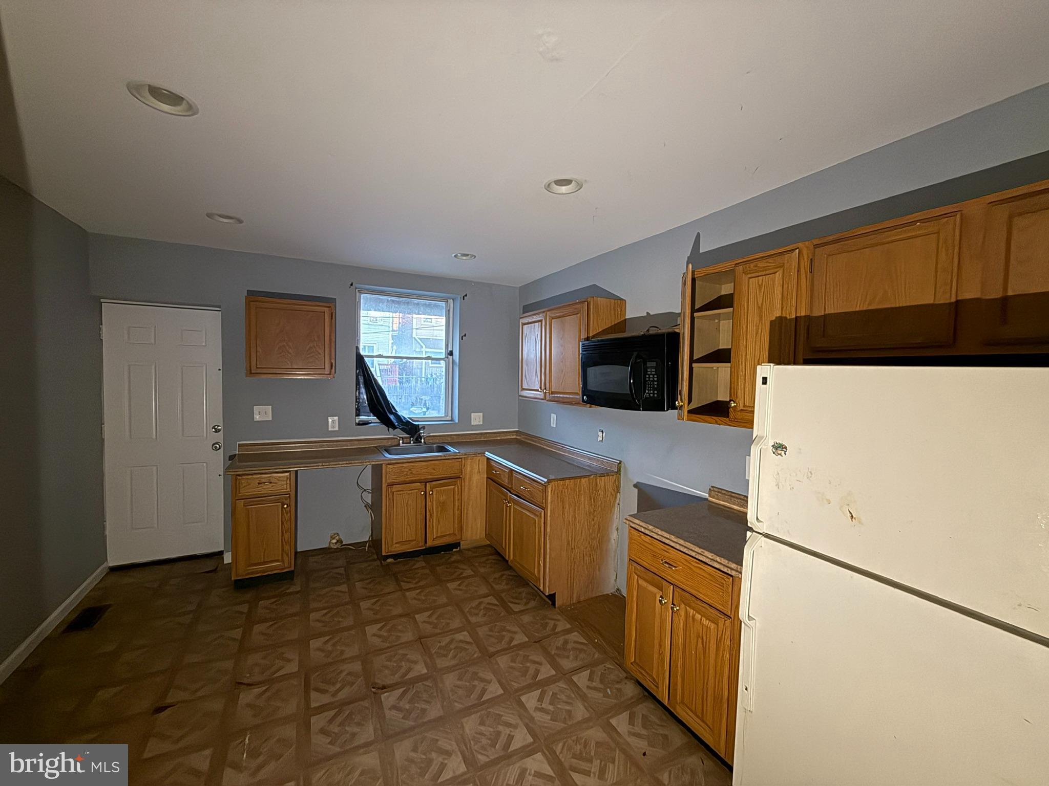 117 North Janney Street Baltimore, MD 21224 - Photo 3 of 13 a kitchen with a sink a stove top oven a refrigerator and white cabinets