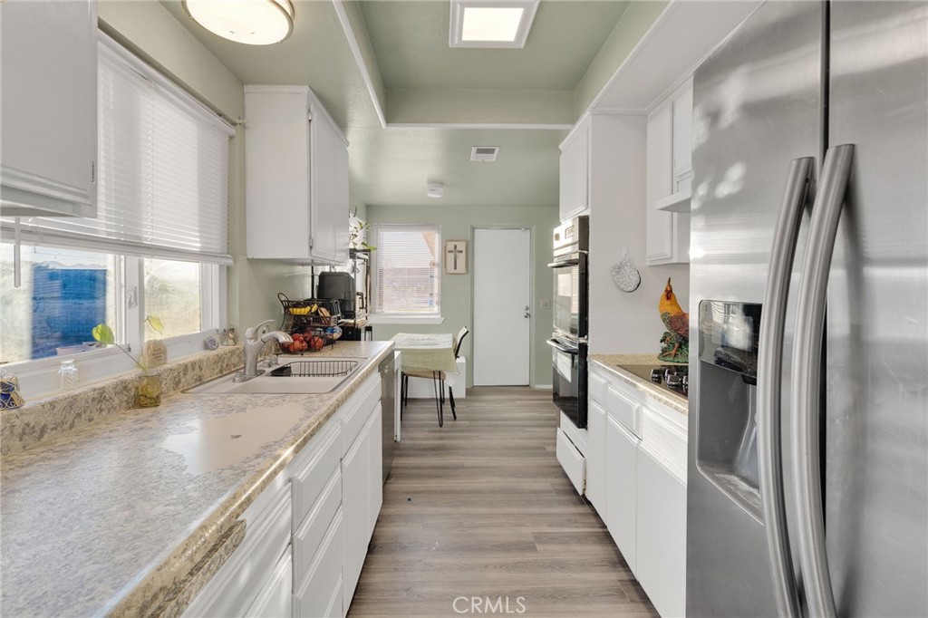 13167 Olathe Road Apple Valley, CA 92308 - Photo 13 of 40 a view of a kitchen with kitchen island a large counter top space a sink stainless steel appliances and cabinets