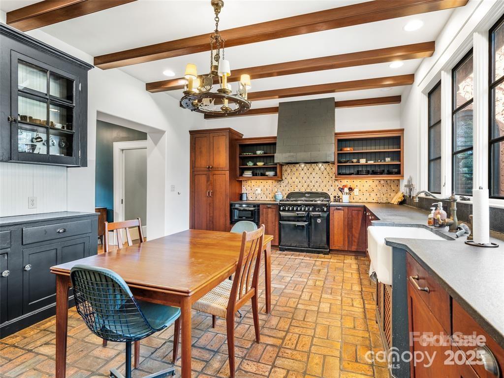26 Sheridan Road Asheville, NC 28803 - Photo 20 of 46 a kitchen with stainless steel appliances granite countertop a stove top oven a sink dishwasher a dining table and chairs with wooden floor