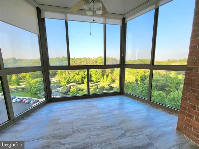 a view of an empty room with wooden floor and windows
