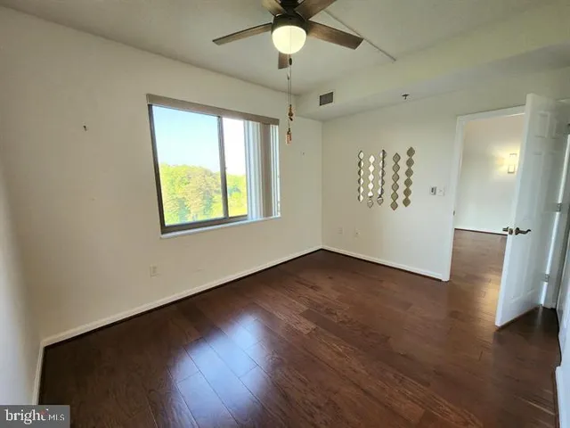 a view of an empty room with wooden floor and a window