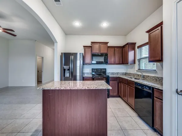 a large kitchen with stainless steel appliances granite countertop a refrigerator and a stove top oven