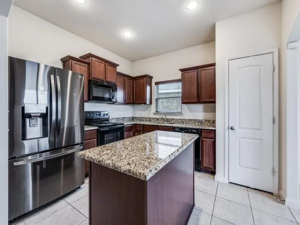 a kitchen with stainless steel appliances granite countertop a refrigerator and a stove top oven